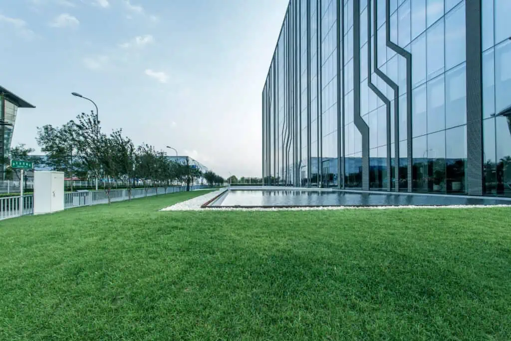 Well-maintained green lawn with modern glass building in the background.