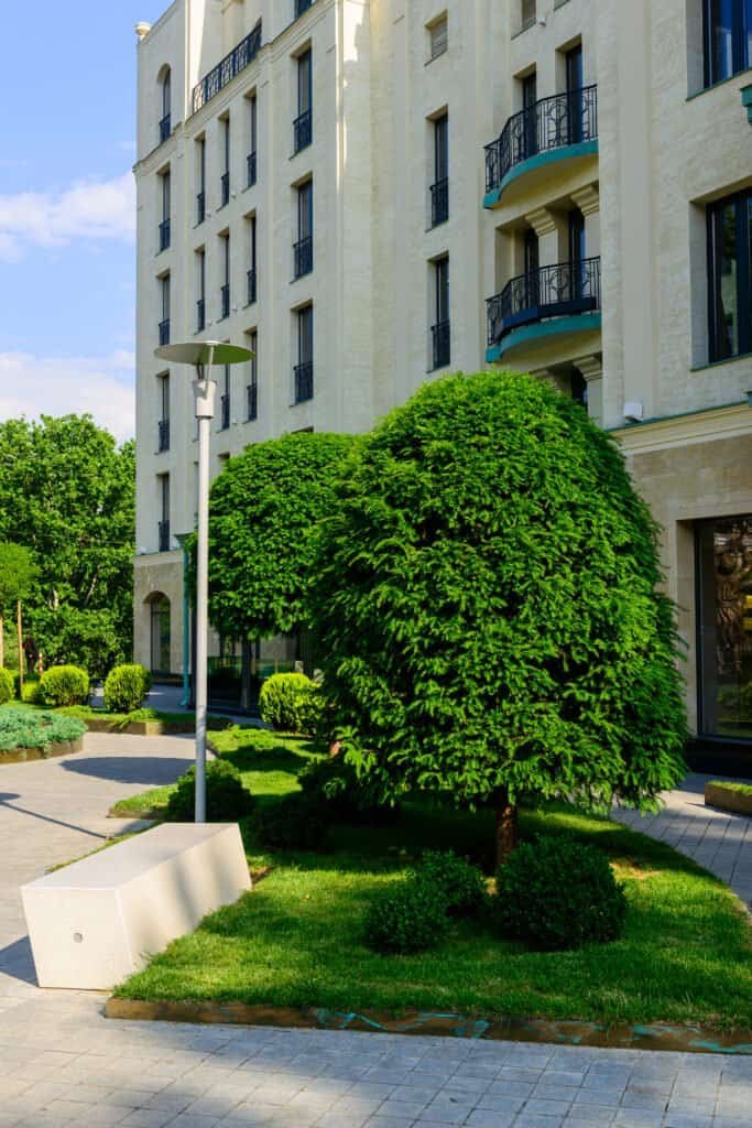 Well-maintained landscaped garden with lush trees and modern building backdrop.